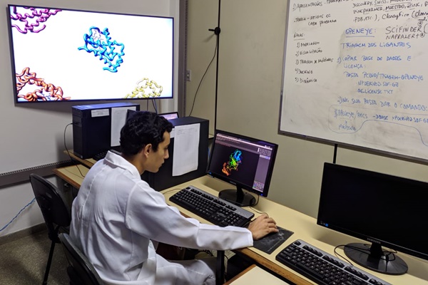 Imagem de um discente e pesquisador da Uesb, sentado à frente do computador realizando pesquisa com moléculas para combater a Covid-19.