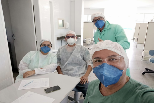 Professor Nilton, com equipamentos de proteção pessoal da área da saúde, com outros três integrantes do grupo Espia trajados da mesma forma.