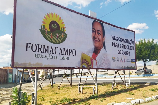 Outdoor com a logo do Programa Formacampo, foto de uma mulher com livros na mão e a frase "mais capacitação para o educador do campo" 