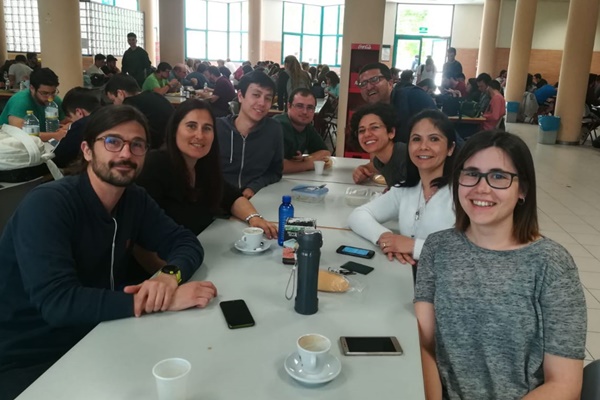 Grupo de pesquisadores sentados à mesa em um prédio onde foi realizado o Pós-Doutorado